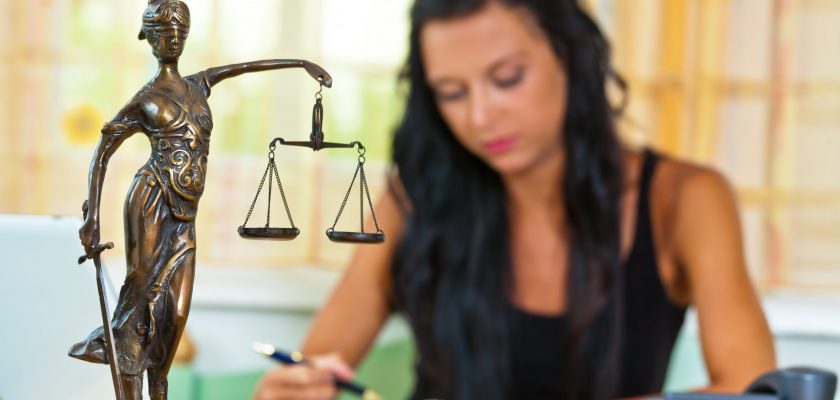 A successful lawyer in the office of justice figure in the foreground.